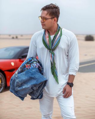 Professional Dubai photographer capturing man posing with red Ferrari.